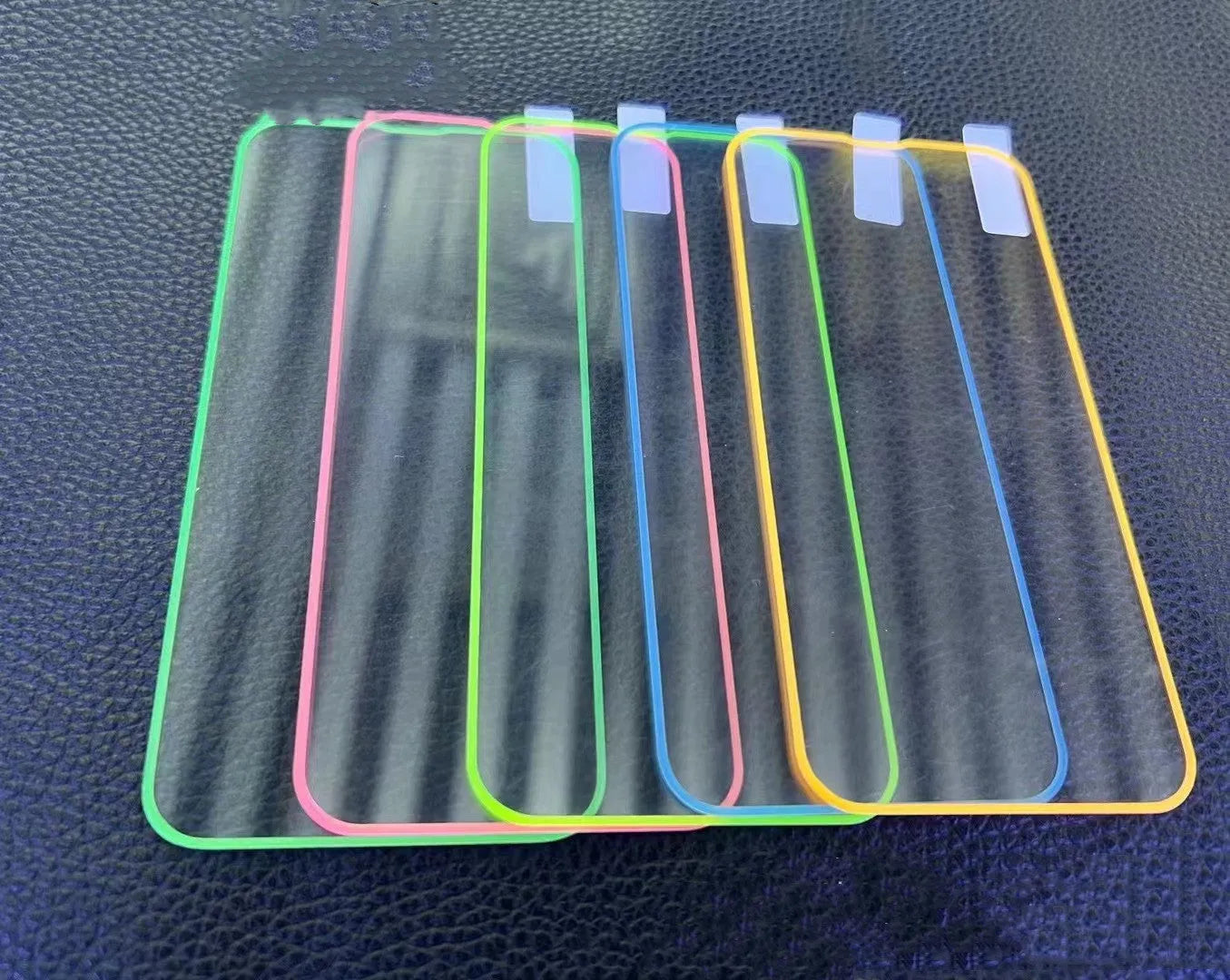 Fluorescent glowing tempered glass screen protector for iPhone on a dark background.