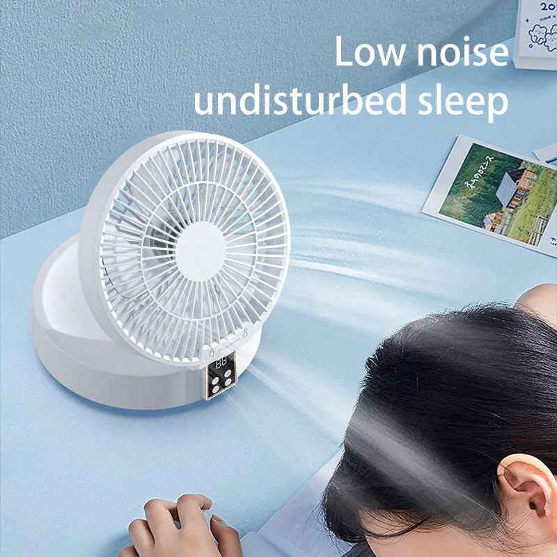 White portable USB folding desk fan with remote control and warm night light on a table.
