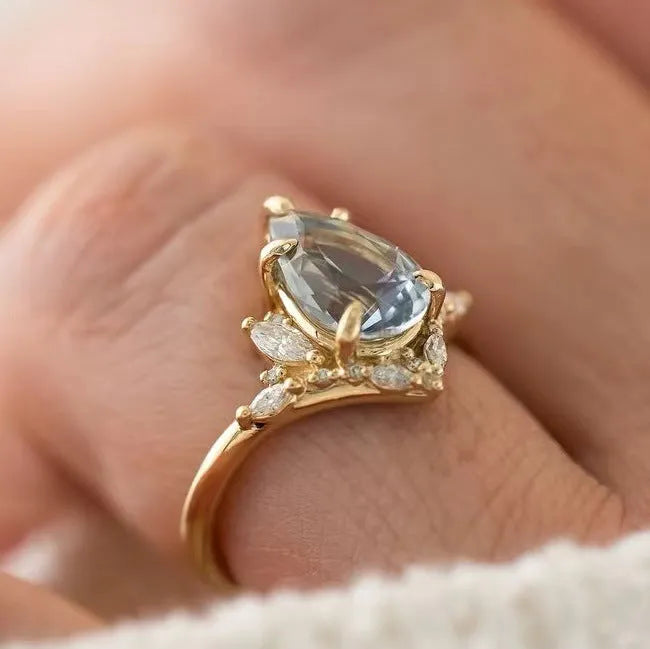 Gold alloy ring with blue crystal diamond inlay and floral design on white background