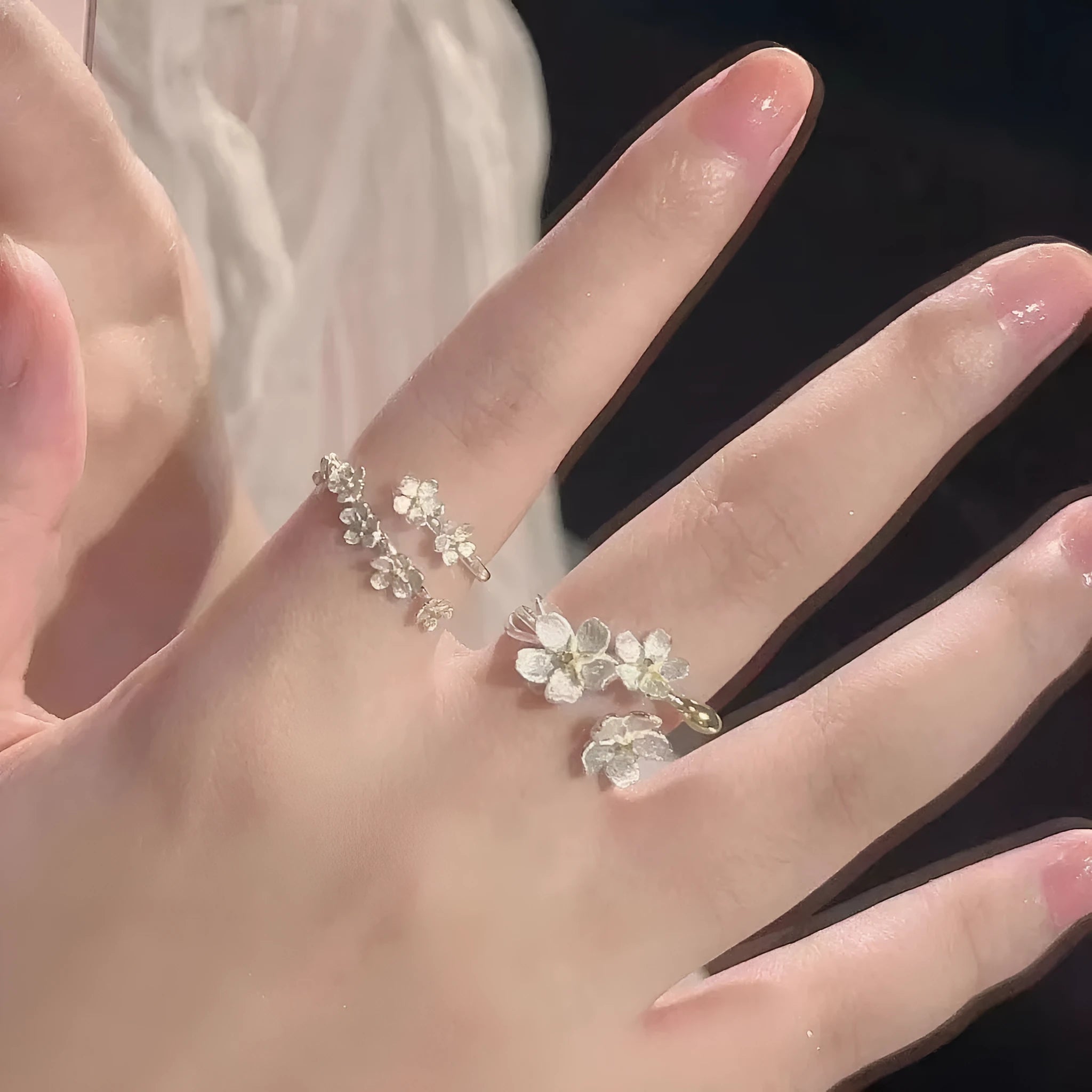 Three-dimensional zinc alloy jasmine flower ring with open mouth design on a finger.