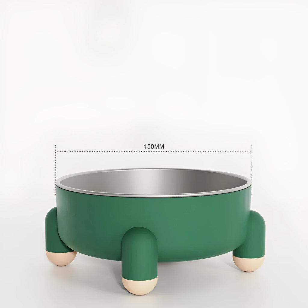 Green stainless steel pet bowl with a non-slip rubber ring and raised foot design on a wooden floor.