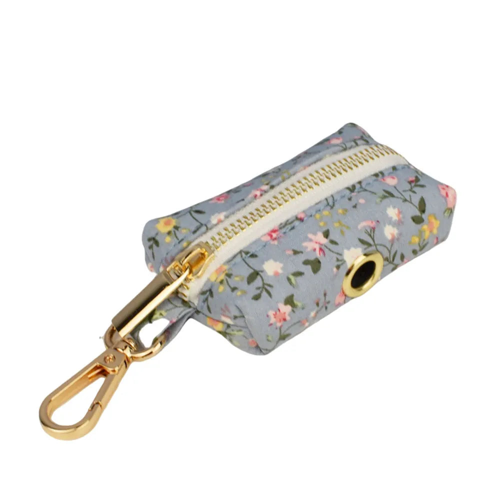 Blue floral pattern dog collar with matching leash, bow tie, vest and waste bag accessories on white background