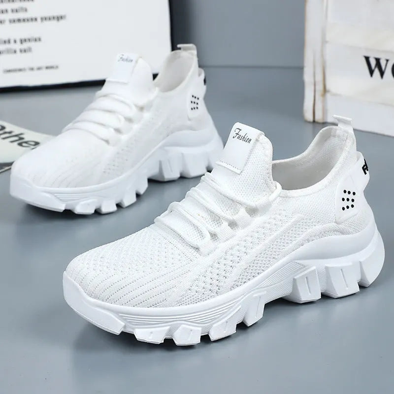 Women's white Flyknit lace-up sneakers with a thick PVC sole and round toe on a neutral background