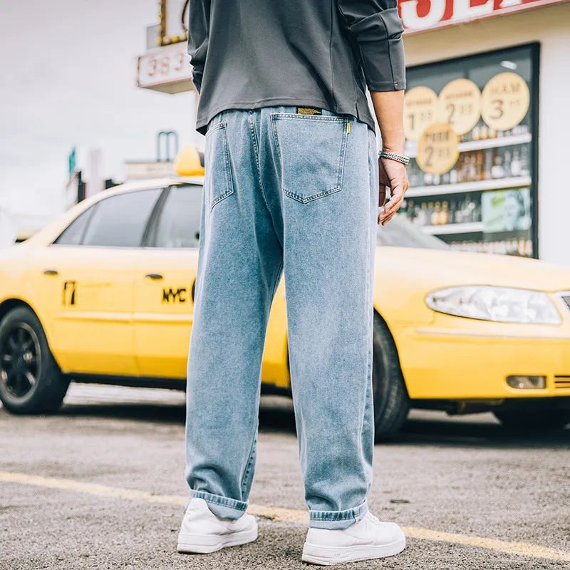 Men's loose straight-cut cotton jeans in dark blue, shown on a man in a casual setting.
