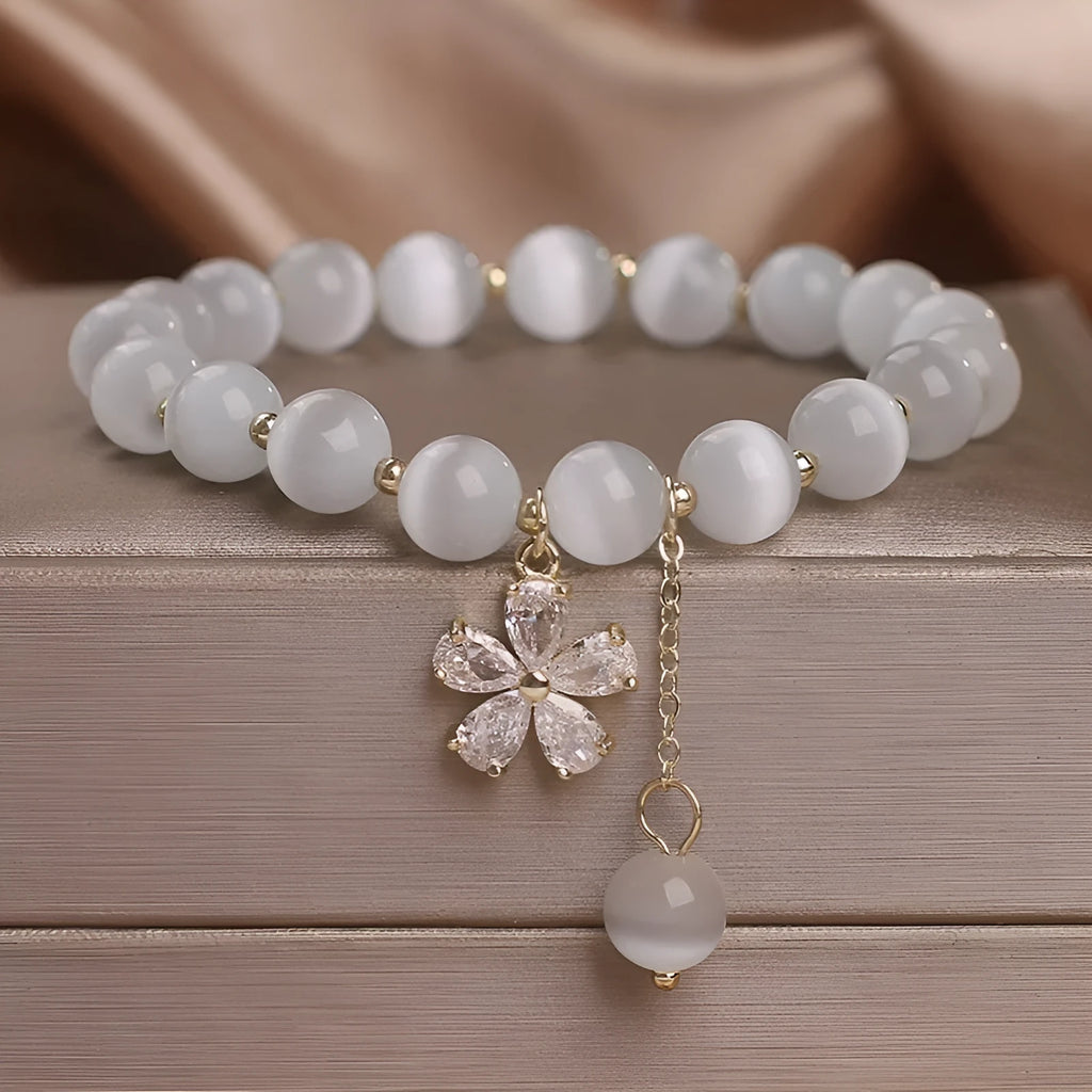 Single loop women's bracelet with white cat's eye stone, small flower tassel, and morganite safety buckle pendant.