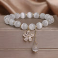 Single loop women's bracelet with white cat's eye stone, small flower tassel, and morganite safety buckle pendant.