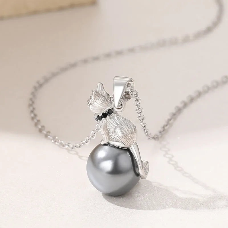 Close-up of a sterling silver cat pendant necklace on a clavicle-length chain, showing the electroplated finish.