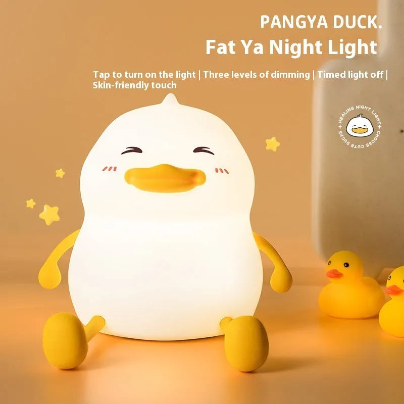 Chubby white silicone night lamp on a desk holding a mobile phone, showing soft LED glow.