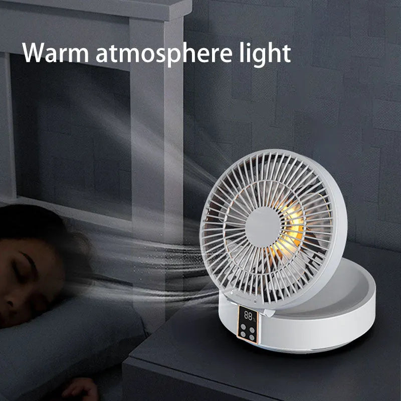 White portable USB folding desk fan with remote control and warm night light on a table.