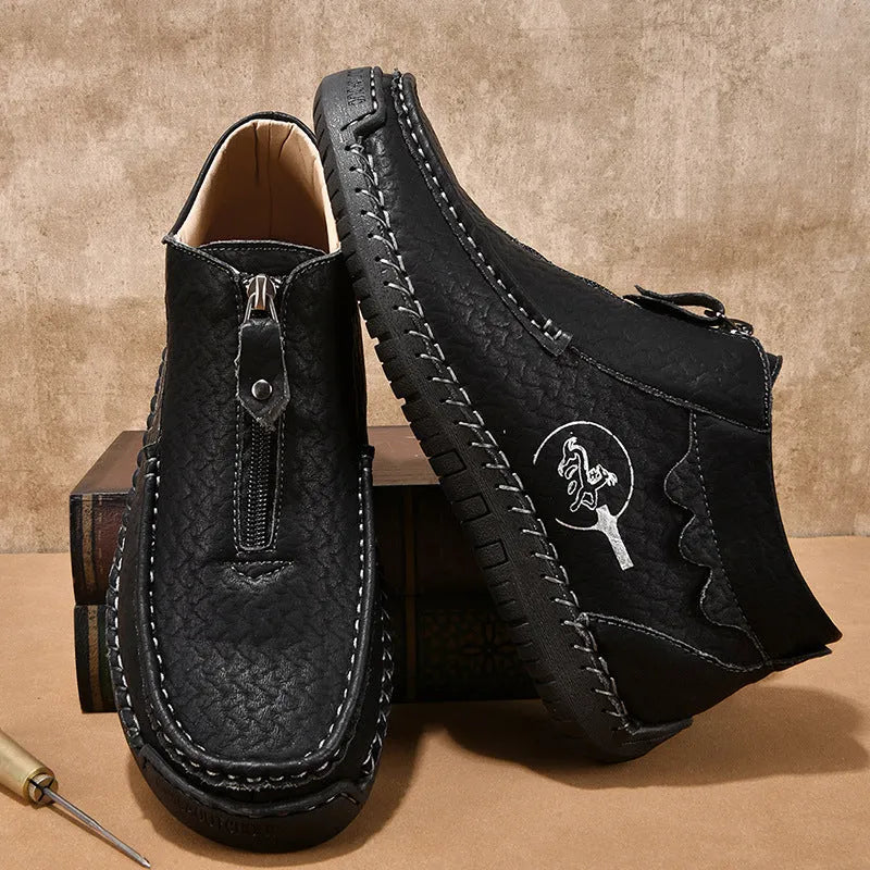 Men's black slip-on leather loafers with round toe and rubber sole, shown in a casual setting.