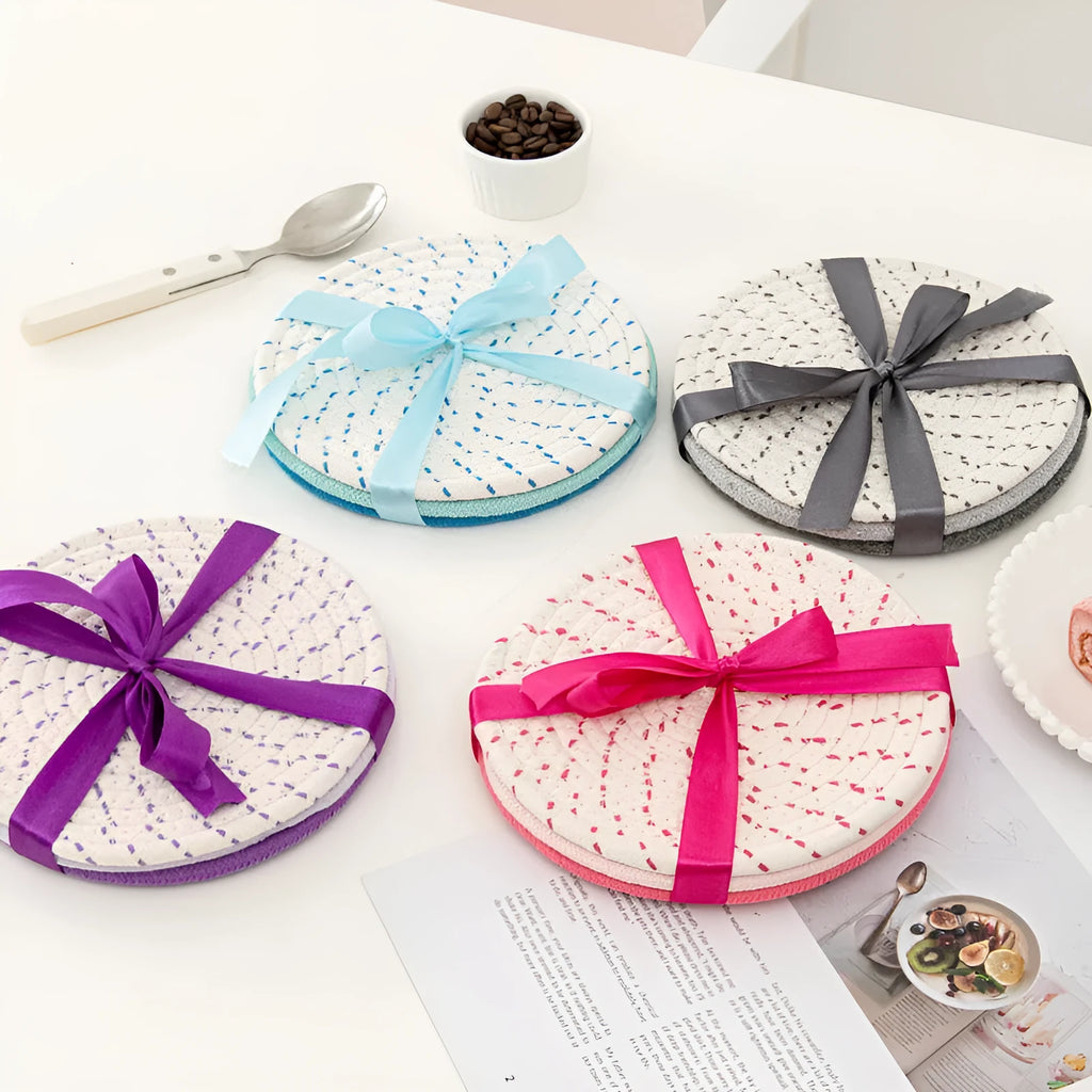 Three round blue cotton cord coaster placemats on a wooden table.