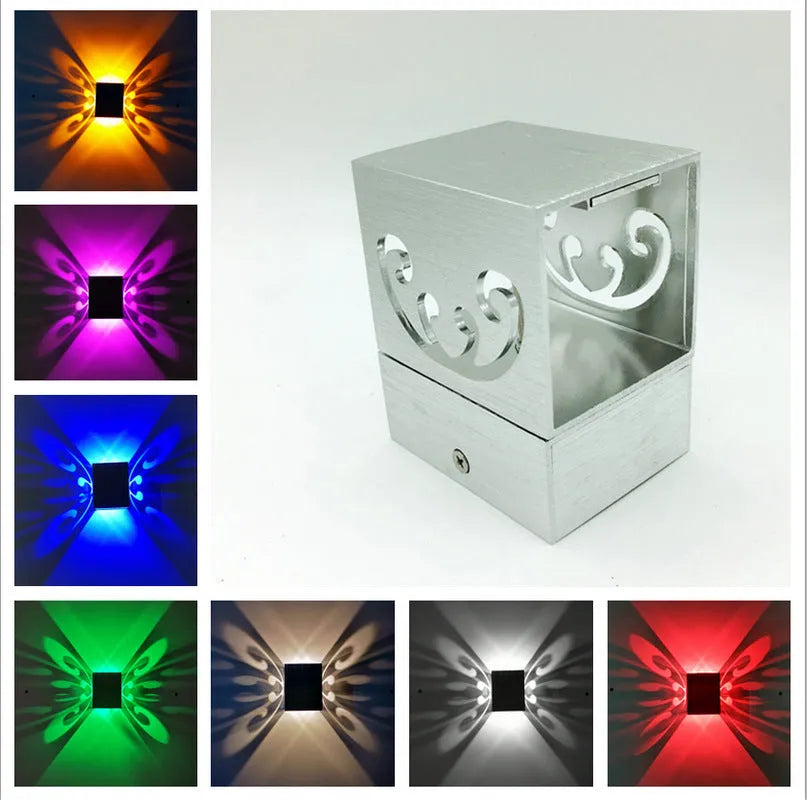 Modern aluminium butterfly-shaped LED wall lamp on a white wall with remote control.
