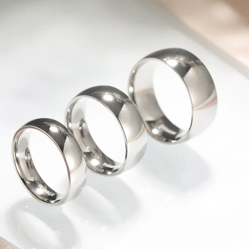 A simple silver titanium steel ring on a finger, showing the band's width and uniform ground finish.