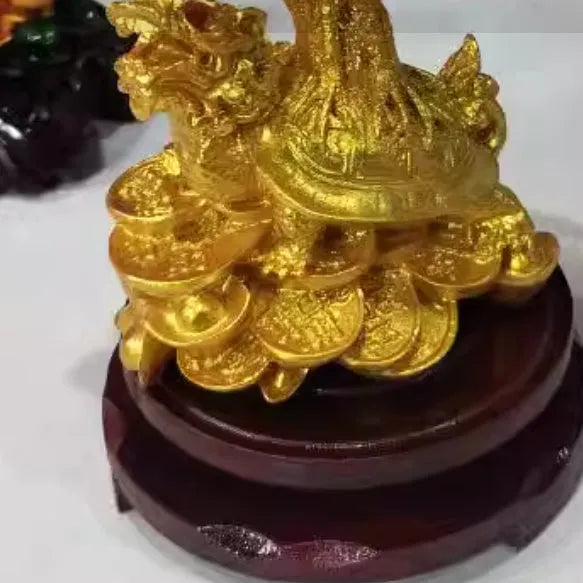 Citrine-coloured resin turtle money tree ornament on a neutral background.
