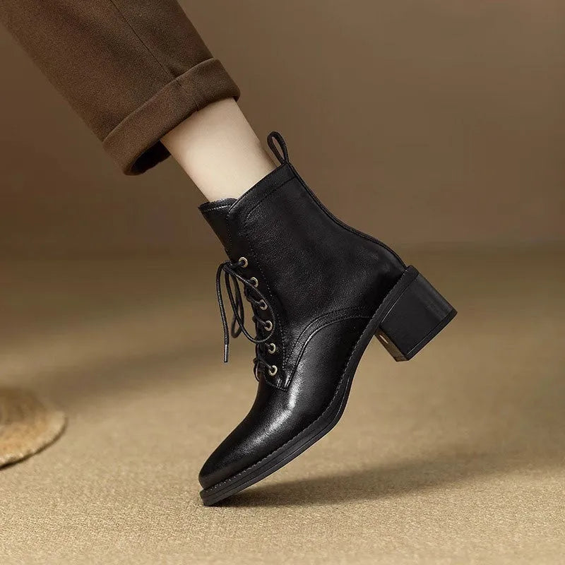 Women's black pointed-toe short tube ankle boots with a low block heel on a neutral background.