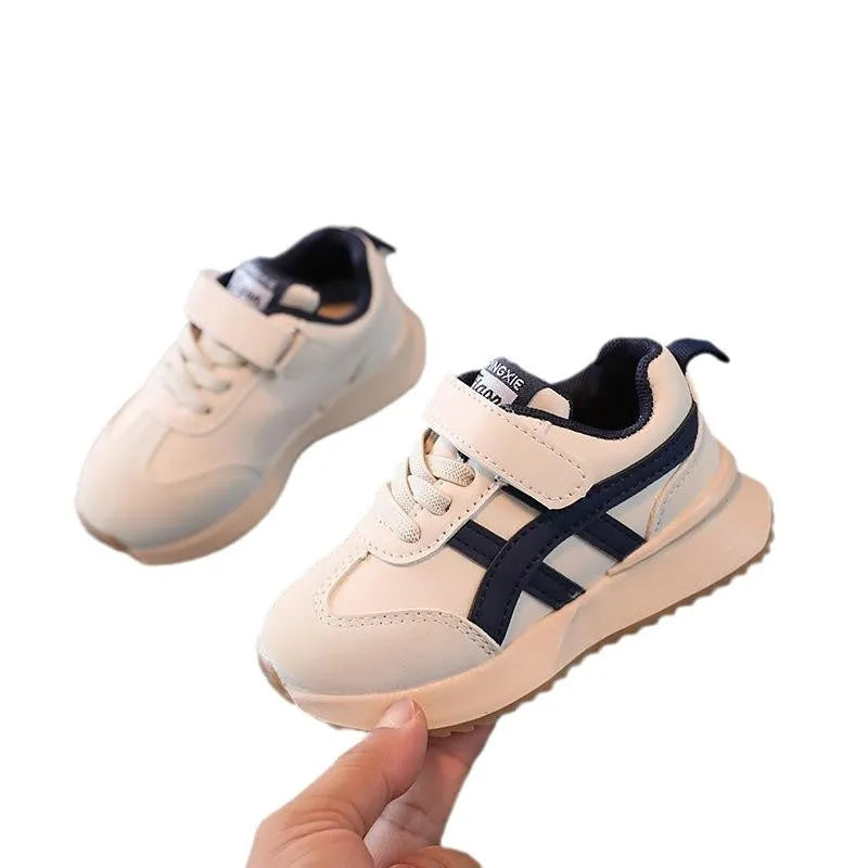 Children's white synthetic leather sneaker with Velcro strap on a rubber sole.