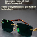 Frameless dark green crystal sunglasses shown with a glasses case and a lens cloth.