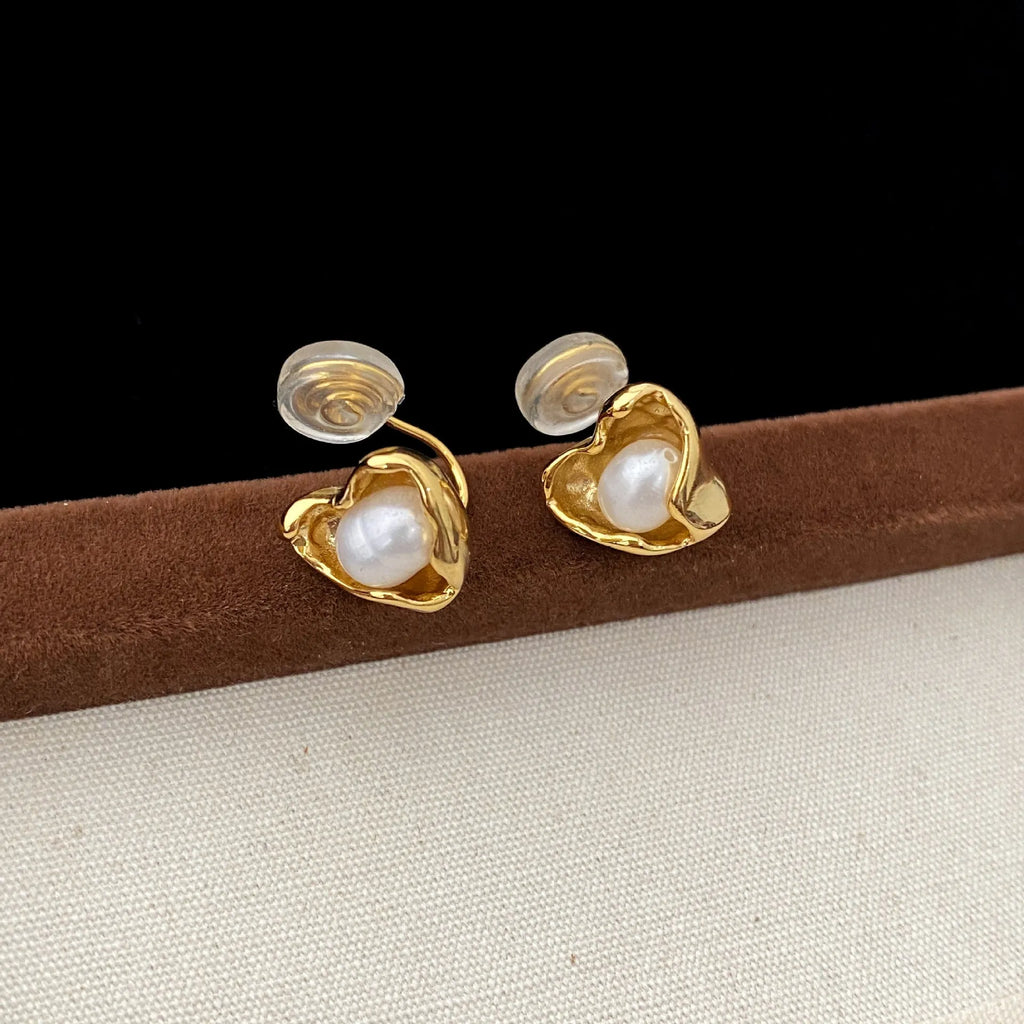 Pair of copper heart shaped irregular pearl earrings with electroplating finish on white background