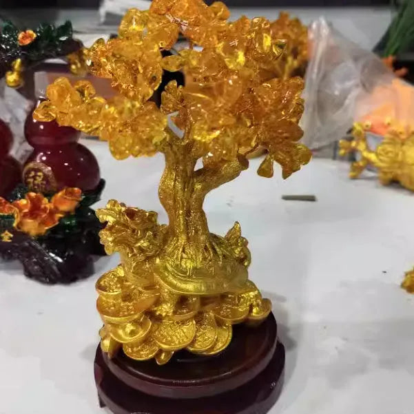Citrine-coloured resin turtle money tree ornament on a neutral background.