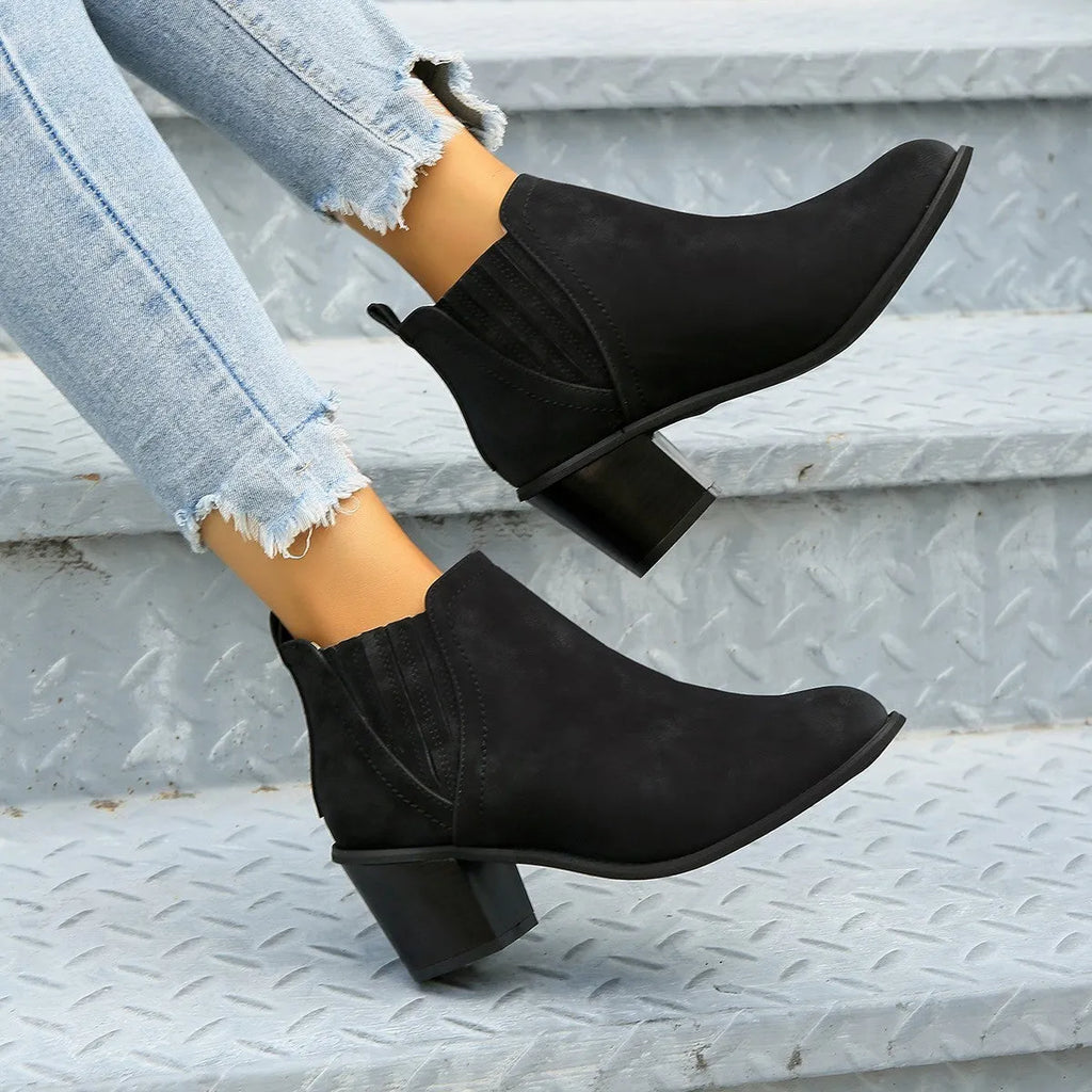 Black women's slip-on ankle boots with a pointed toe and a thick, low square heel on a rubber sole.