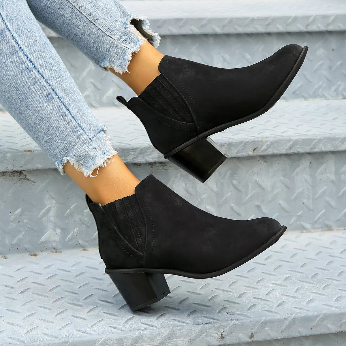 Black women's slip-on ankle boots with a pointed toe and a thick, low square heel on a rubber sole.