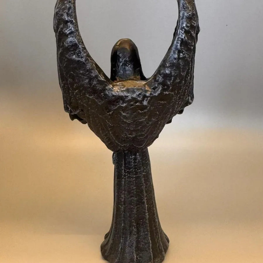 Small dark angel resin statue ornament on a table, showing detailed wings and robe.