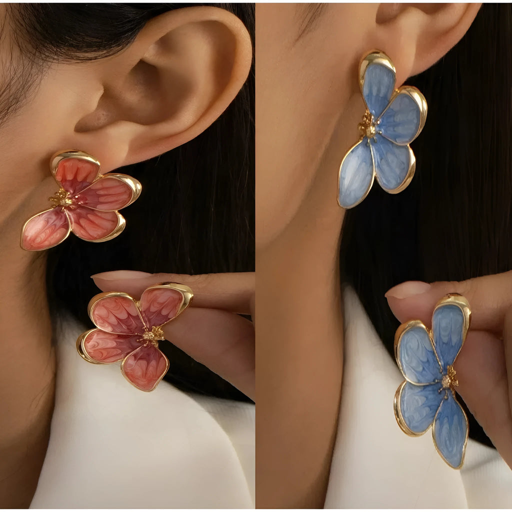 Three-dimensional flower earrings in blue and red colour options on a neutral background