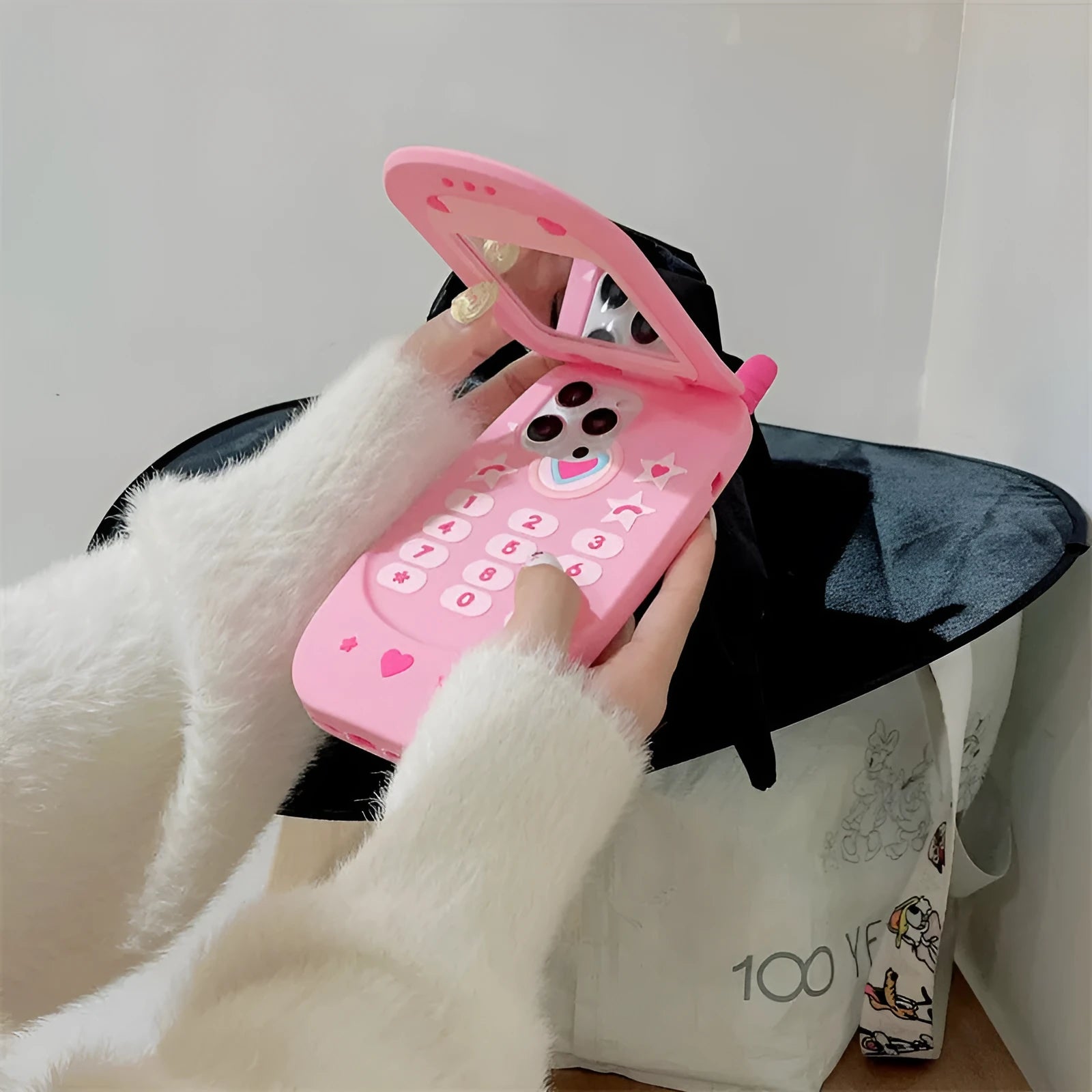 Light pink silicone flip phone case with built-in mirror for iPhone, showing cute cartoon design