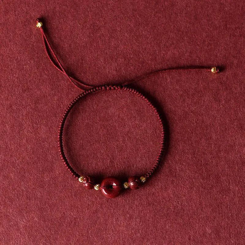 Traditional Chinese cinnabar bracelet with heart-shaped centrepiece and peace buckle clasp on coloured rope cord