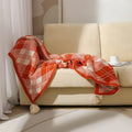 Bohemian-style acrylic sofa blanket with tassel trim shown in a beige and orange colour.