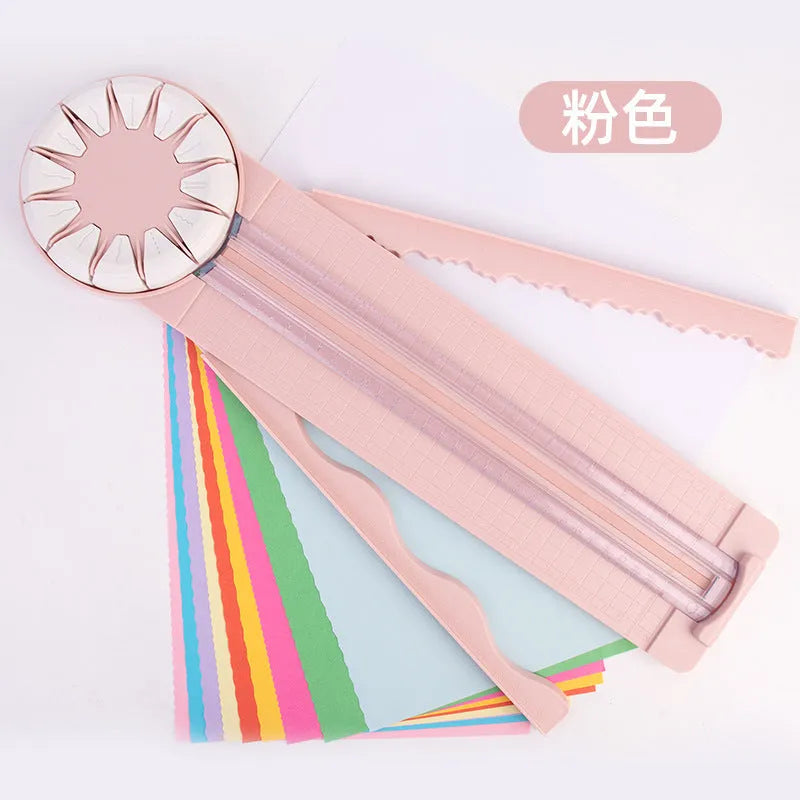 Pink and black 12-in-1 multifunctional plastic paper cutter with dotted guides on a cutting mat.