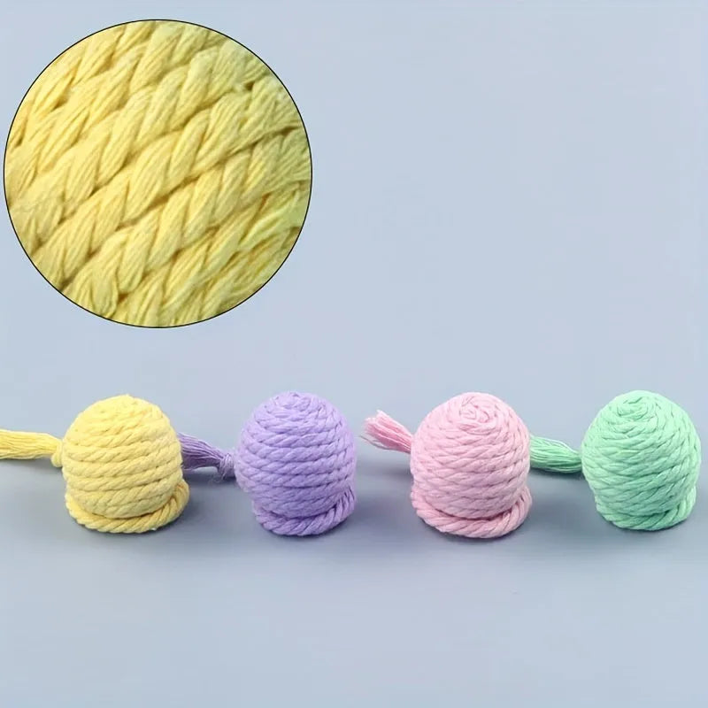 Green cat toy ball with attached rope and internal bell next to a pink one.