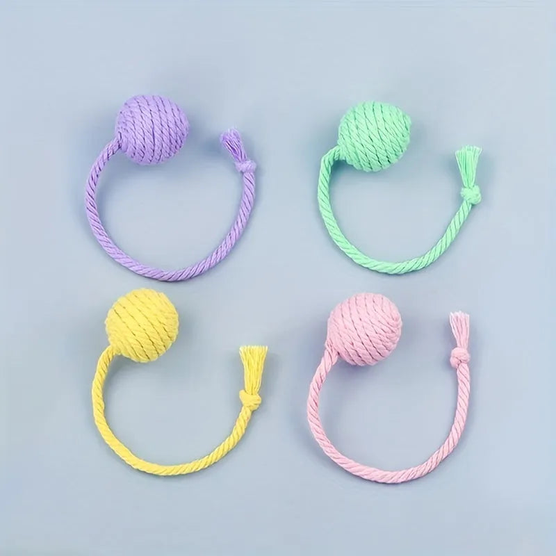 Green cat toy ball with attached rope and internal bell next to a pink one.