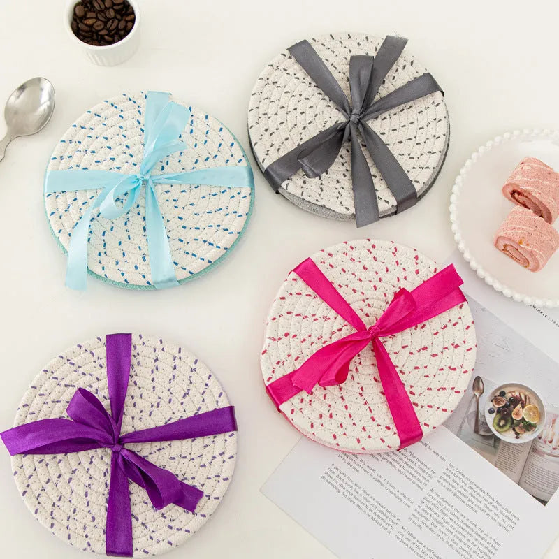 Three round blue cotton cord coaster placemats on a wooden table.