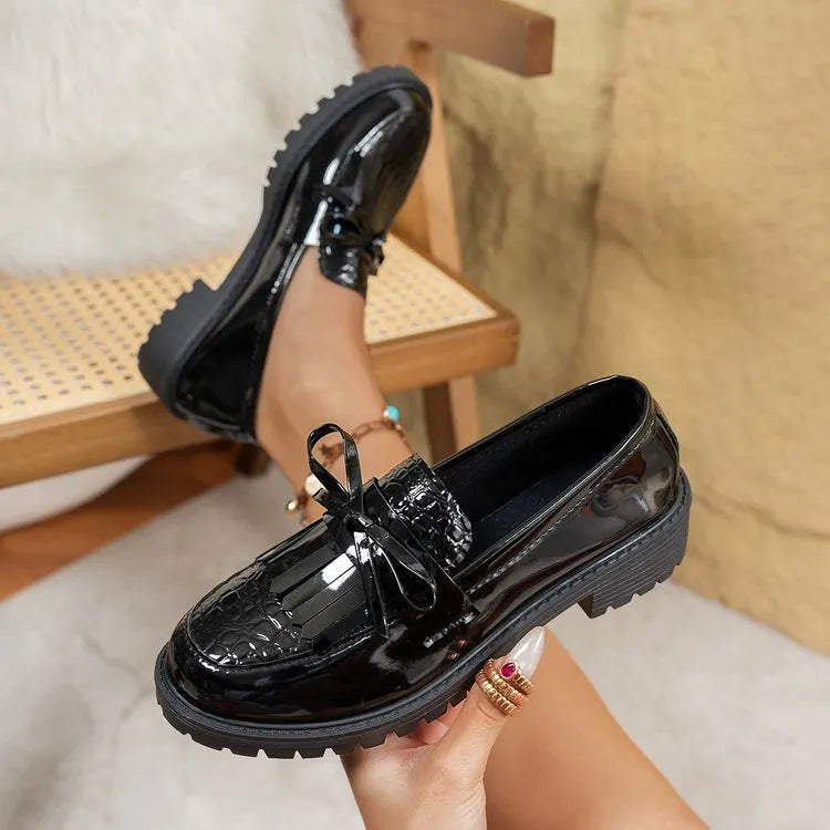 Women's black loafers with a decorative bow on the front.