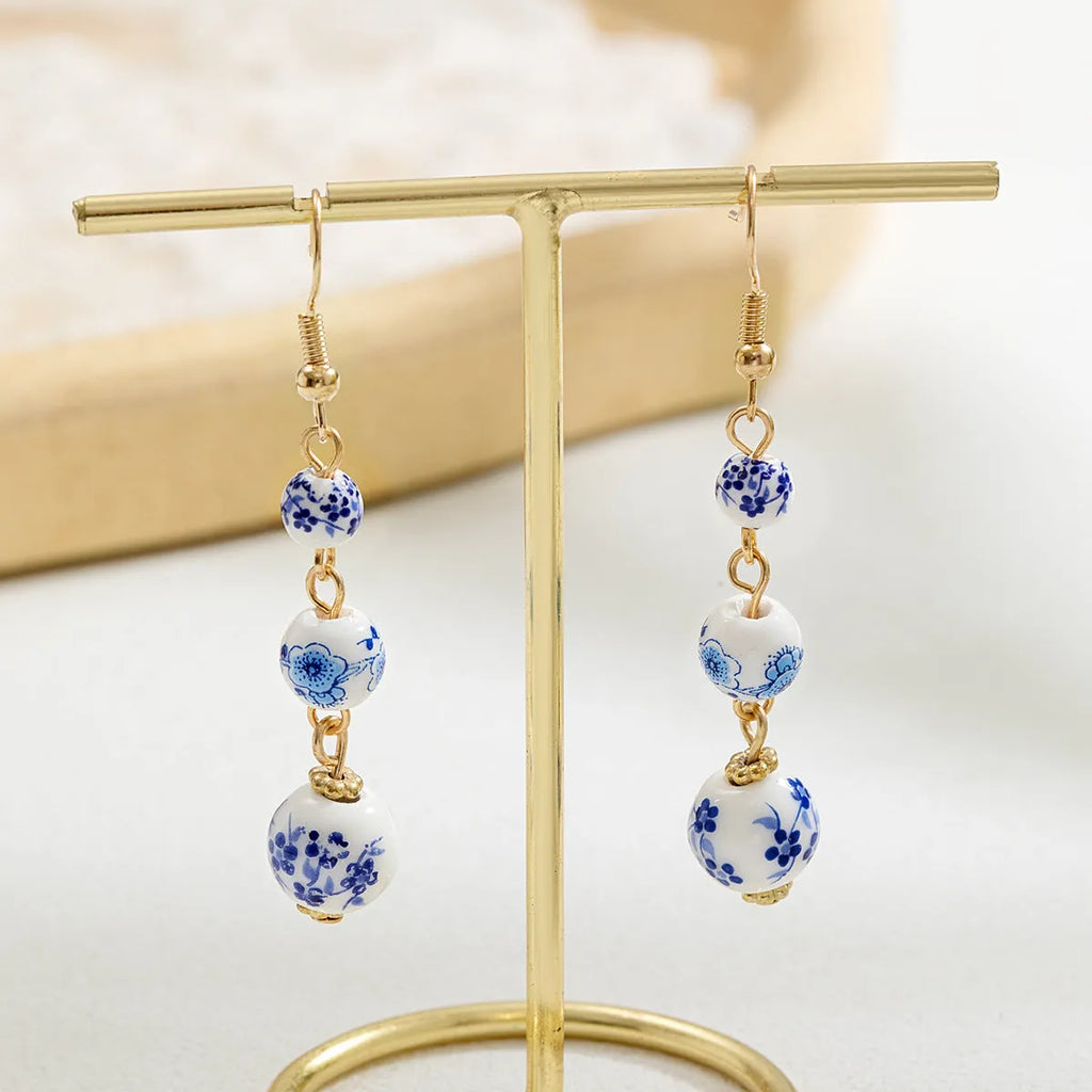 Long retro earrings with blue and white ceramic beads and geometric alloy parts.